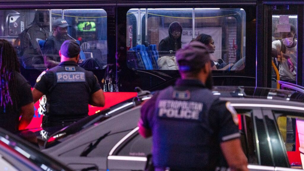 Bus riders watch as Metropolitan Police Department officers detain a man during a traffic stop on H Street corridor in Washington, DC